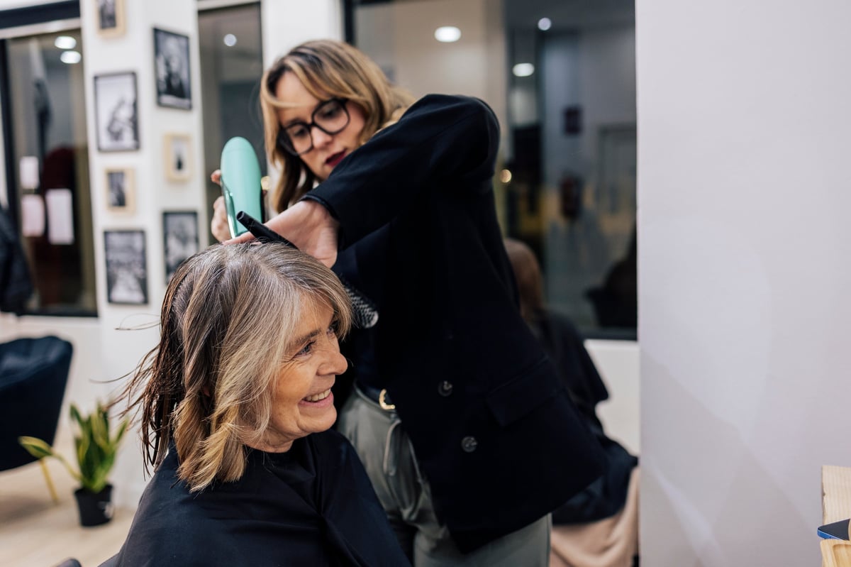 Professional woman hairstylist styling client's hair