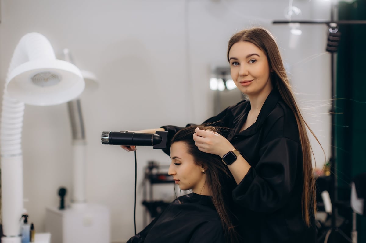 Hairdresser working on client's hair with blow dryer